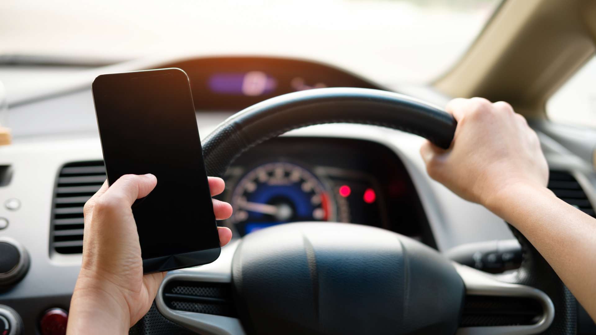 appen-achter-stuur-person-holding-black-smartphone-and-vehicle-steering-wheel-1028742